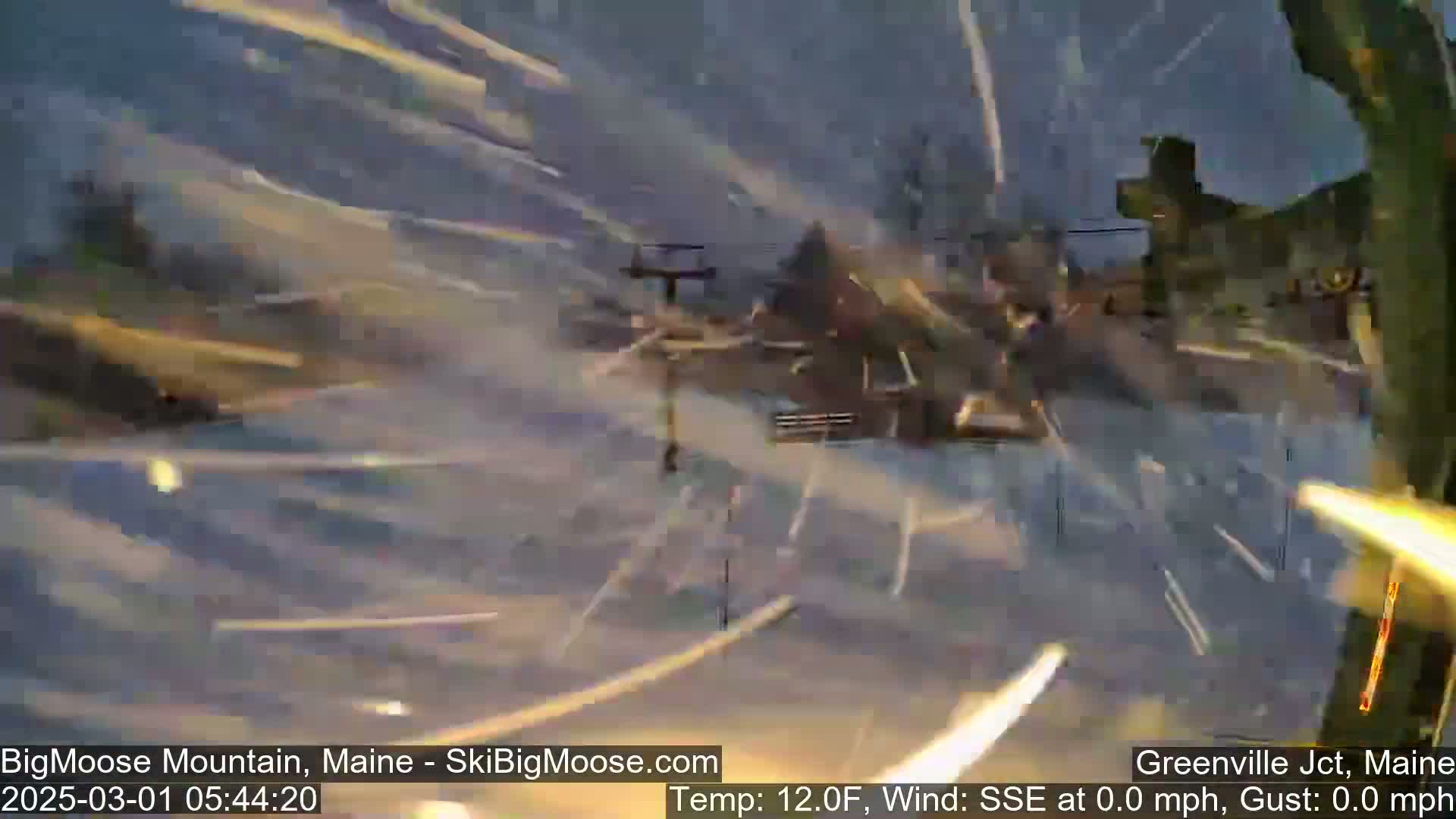 A blurry image shows a snow-covered ski resort with streaks of falling snow in a 12°F wind.