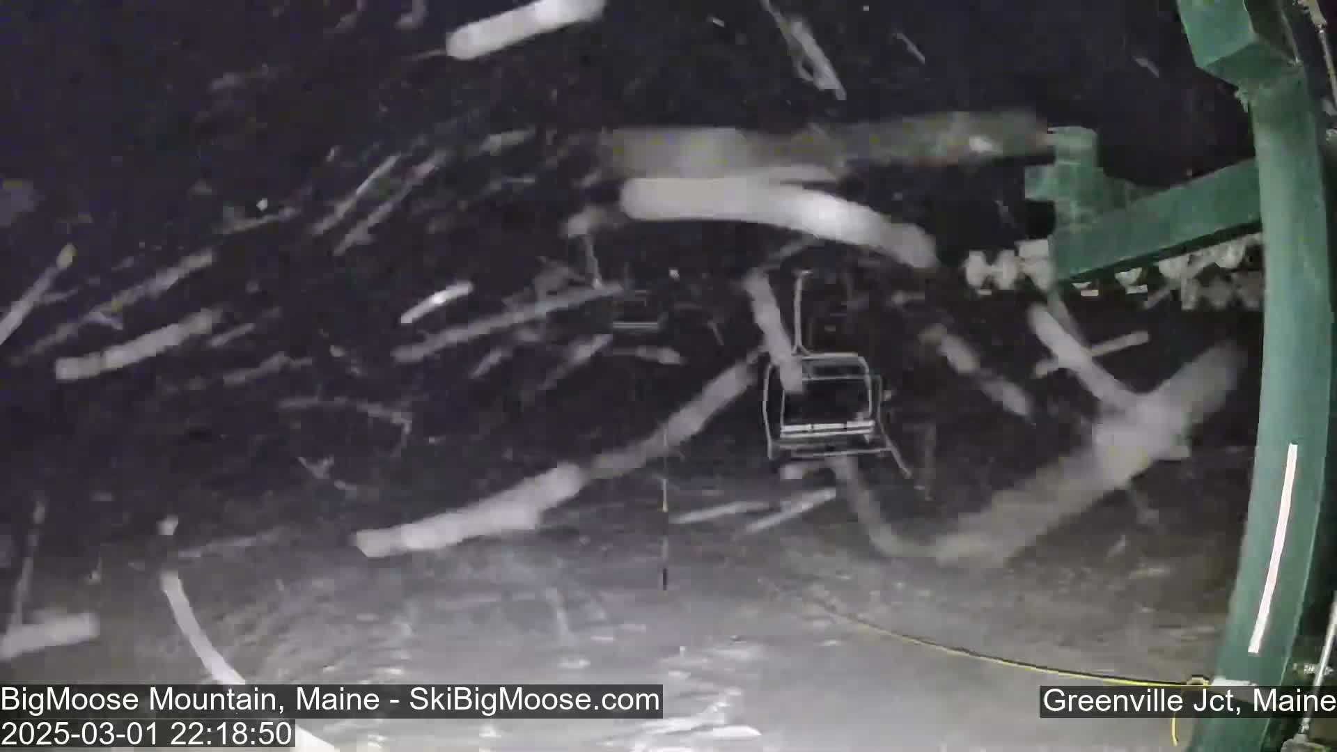A chairlift moves through heavy snowfall at night.