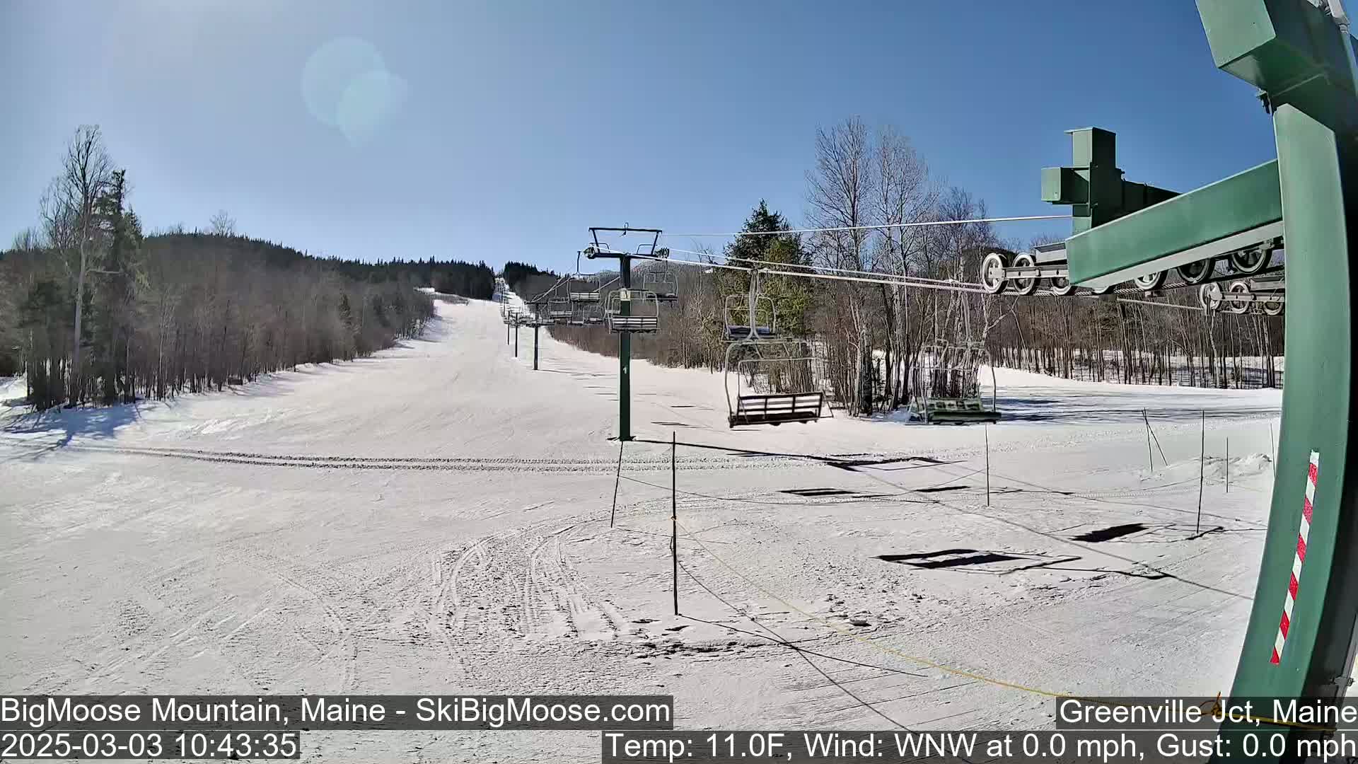 A snow-covered ski slope with a chairlift on a sunny day.