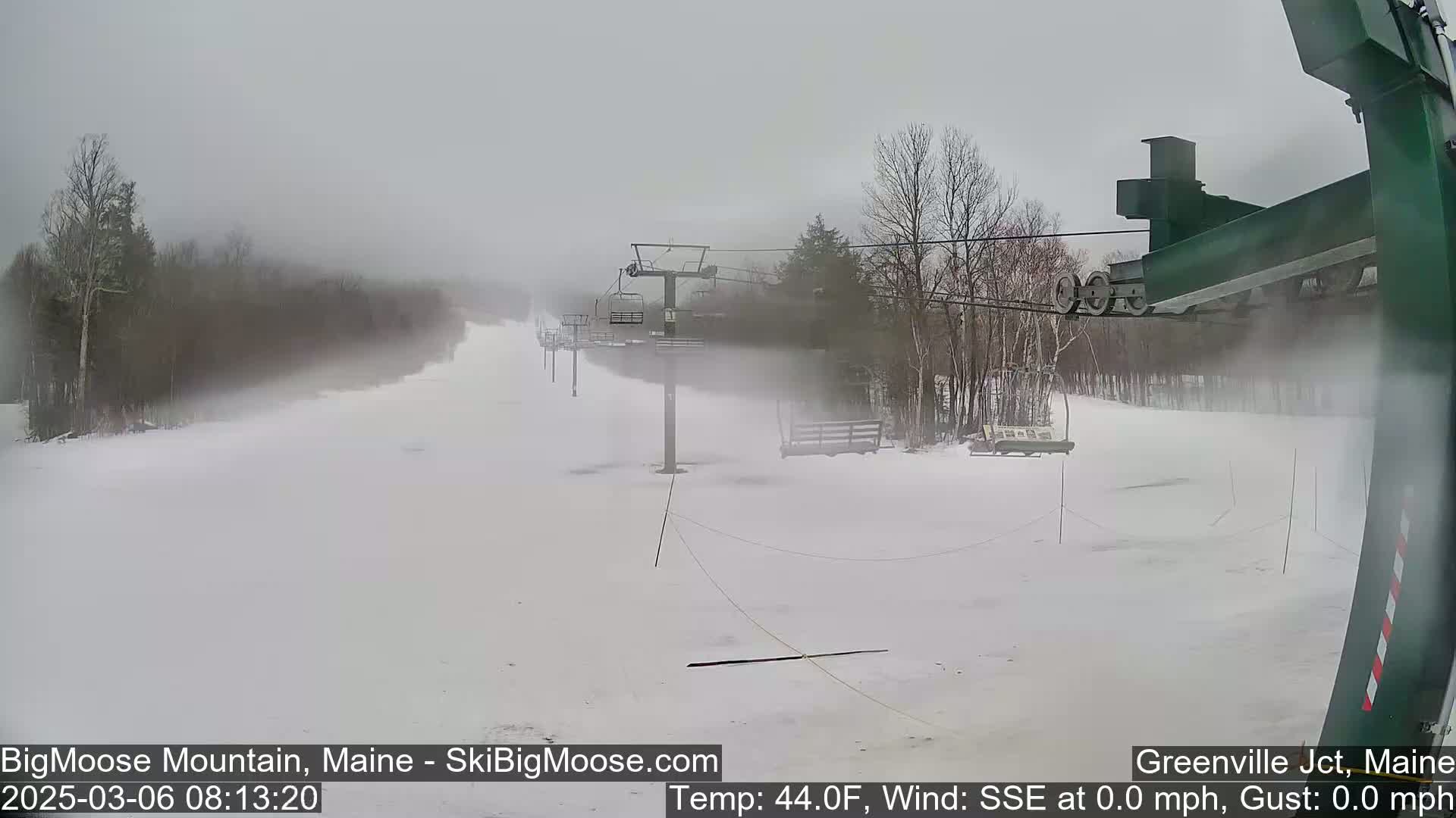 A snow-covered ski slope with chairlifts is visible in foggy conditions.