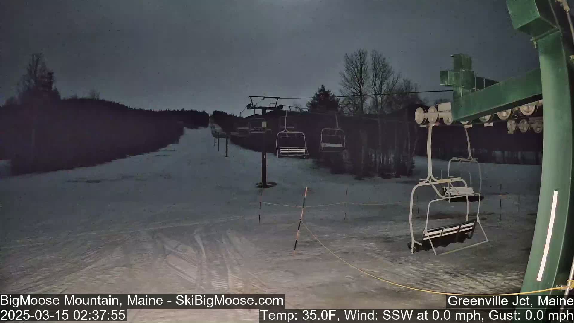 A snow-covered ski lift sits empty under a dark, moonlit sky.