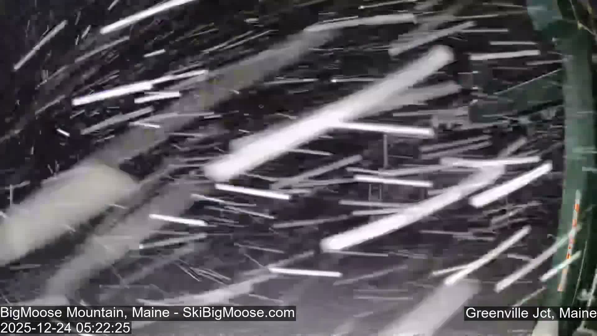 A snow-covered ski slope and empty chairlifts are visible in the dark, cold pre-dawn hours at a ski resort, under a hazy sky.