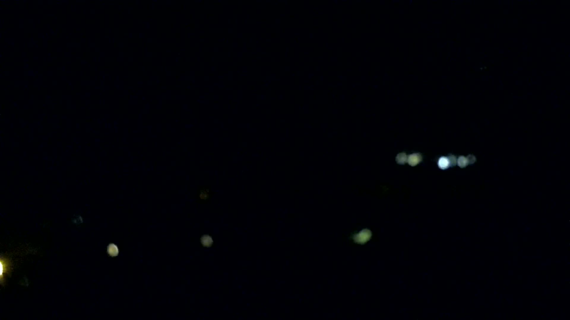 A dark, nighttime scene shows several out-of-focus lights in the distance.