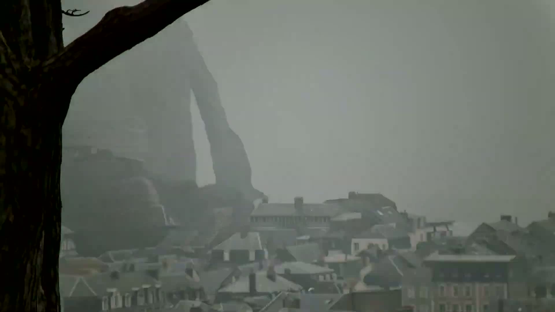 A large, indistinct figure looms over a town shrouded in thick fog.