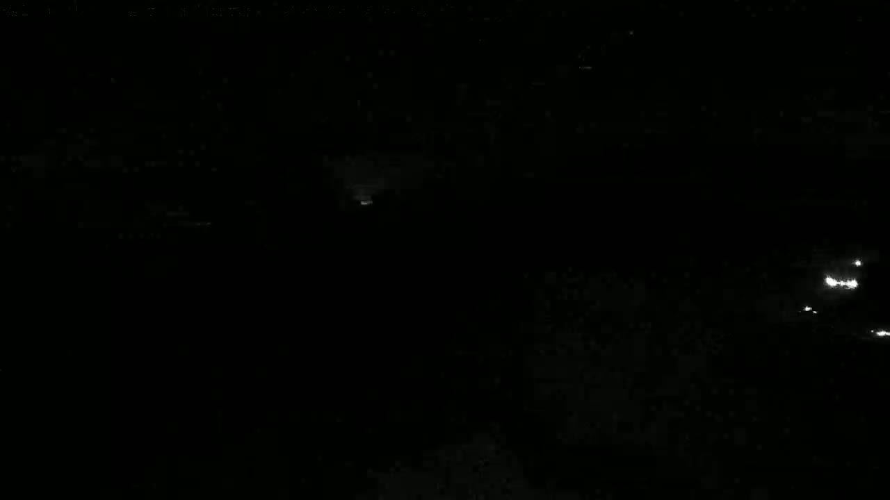 A dark nighttime scene shows a few faint lights in the distance.