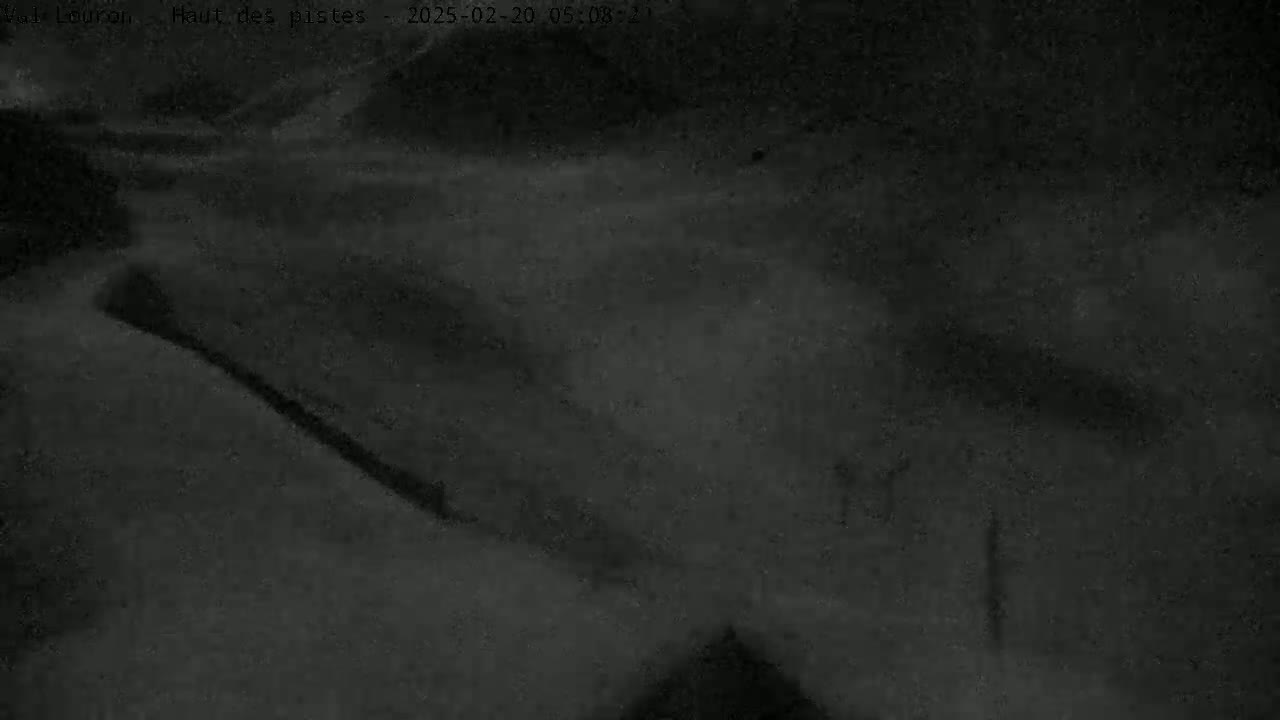 A nighttime, snowy scene shows a dark, indistinct landscape under heavy snowfall.