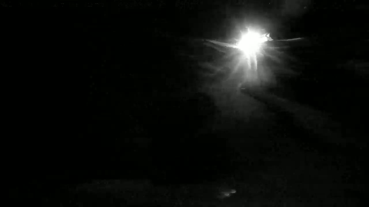 A bright light shines through dark, cloudy night skies.