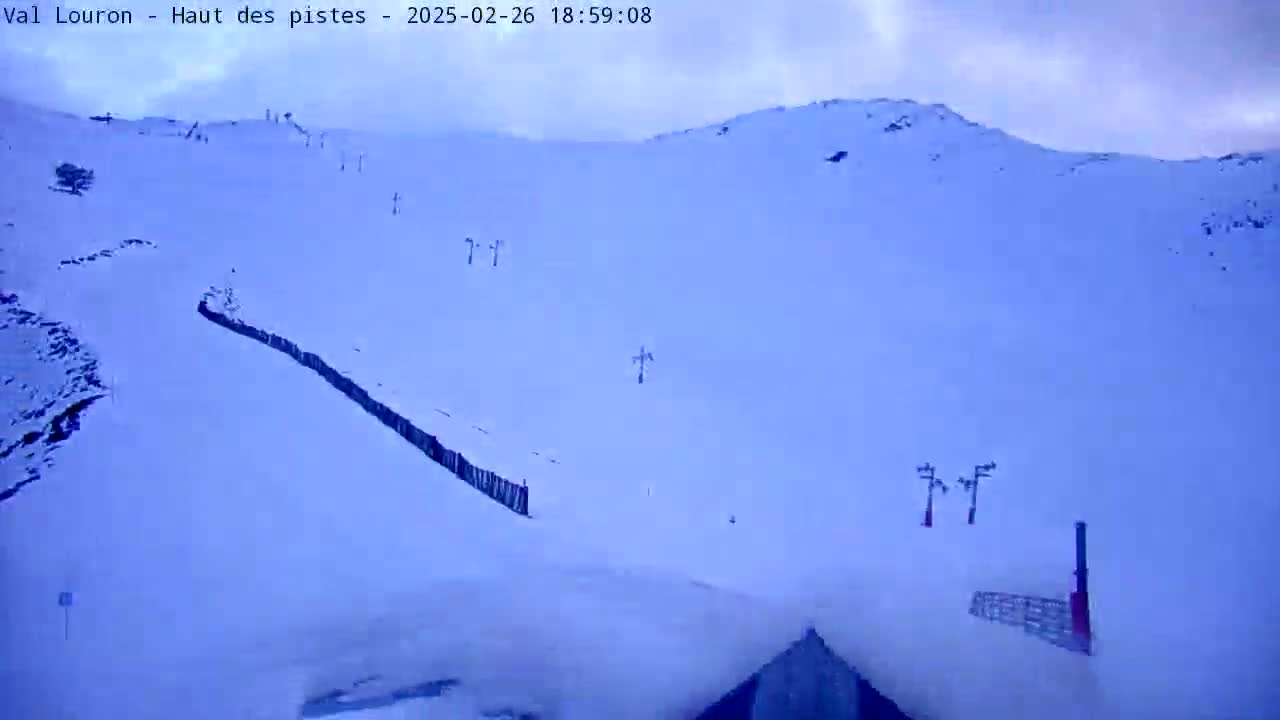 A snow-covered mountain slope with ski lifts under an overcast sky.