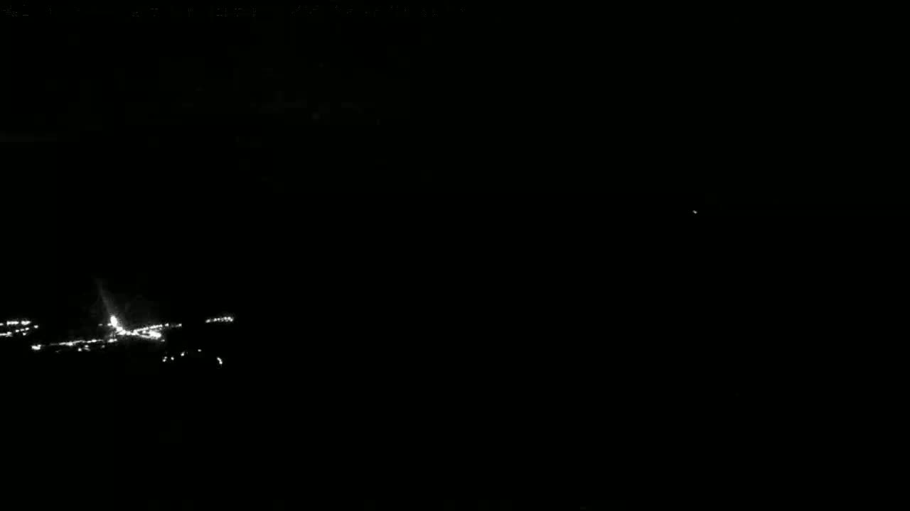 A nighttime, low-light view shows a line of distant, bright lights, possibly a roadway or airport runway.