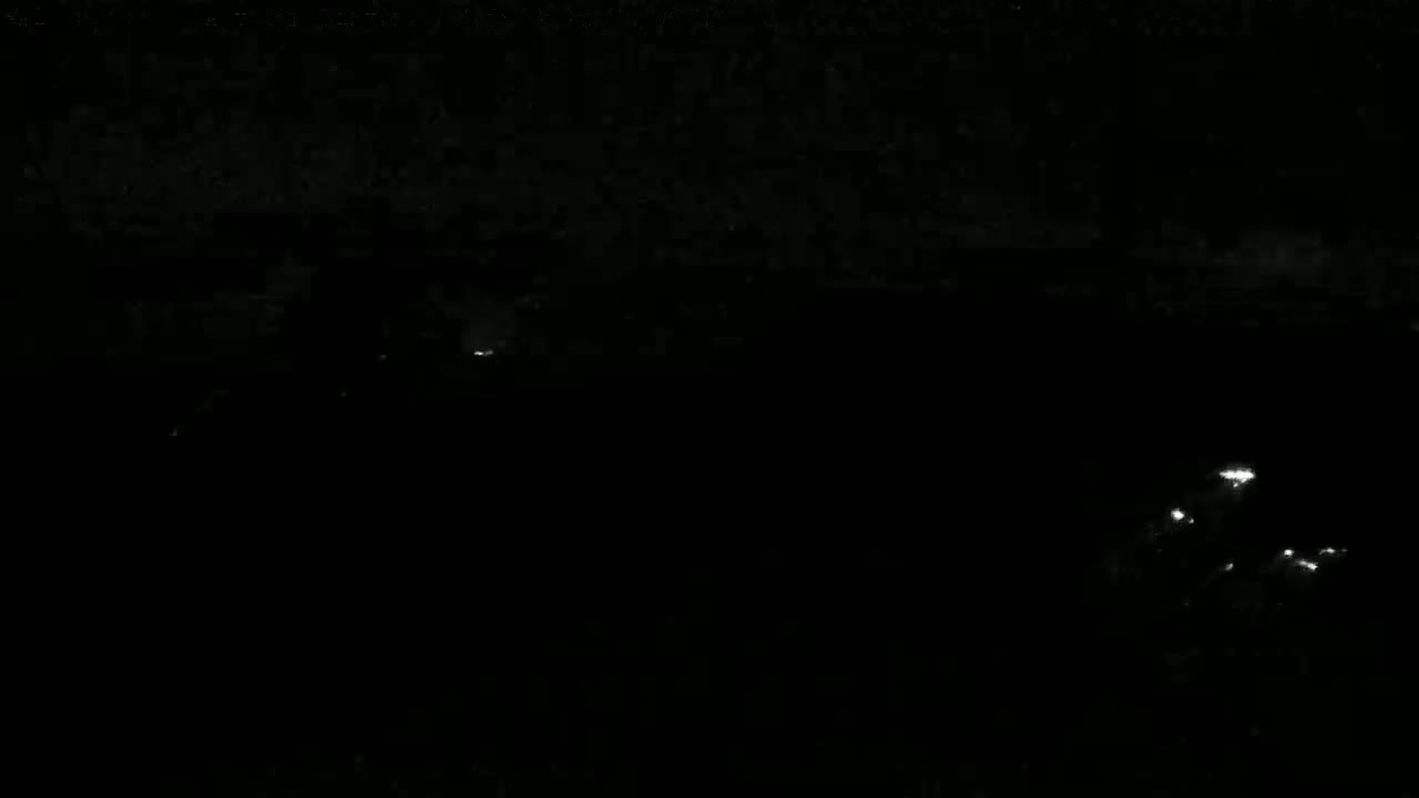 A dark, nighttime scene shows a few faint lights in the distance.