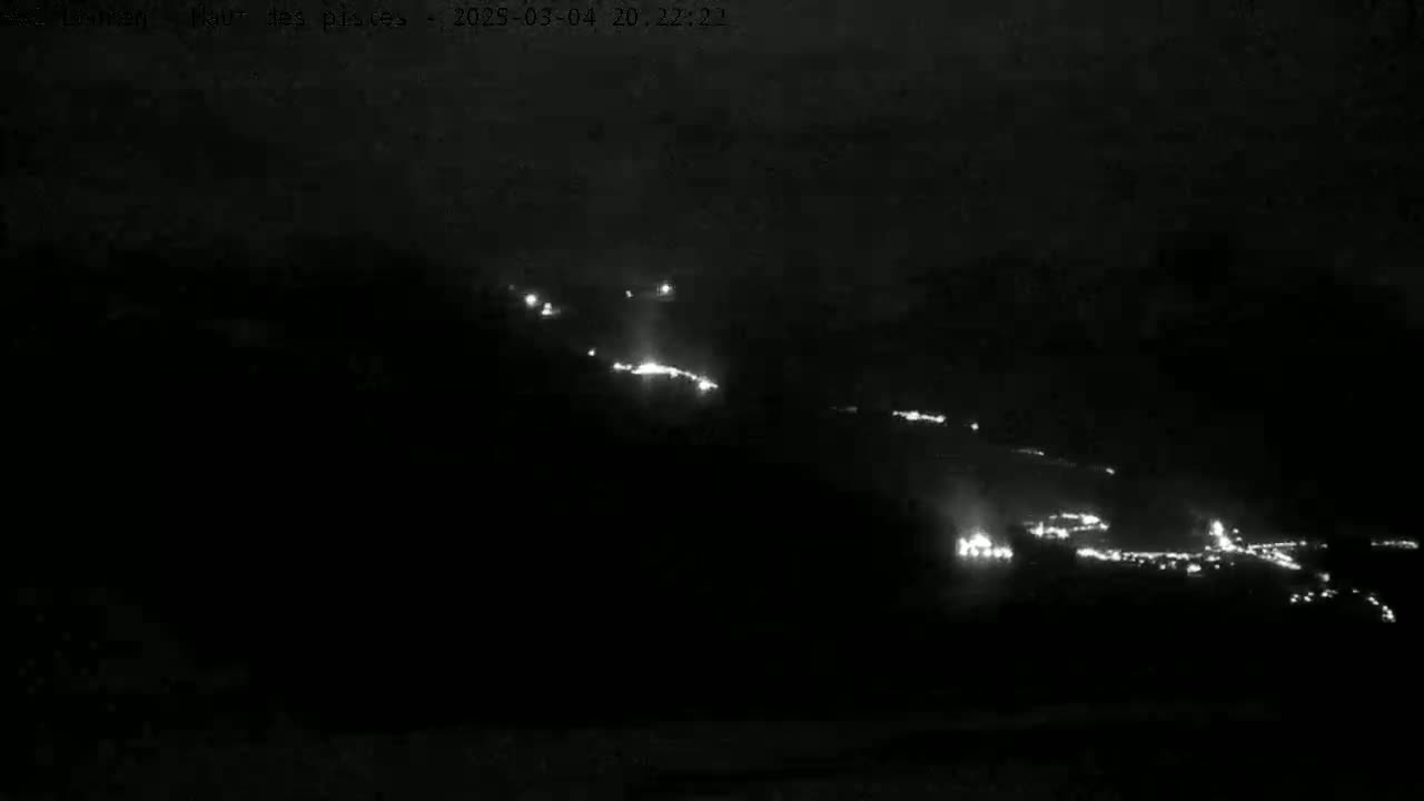 A nighttime, long-range view shows scattered bright lights on a dark hillside.