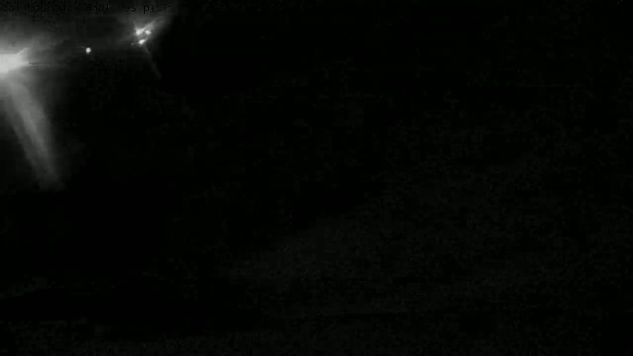 The image shows a dark, nighttime scene with two bright lights and lens flares in the upper left corner.