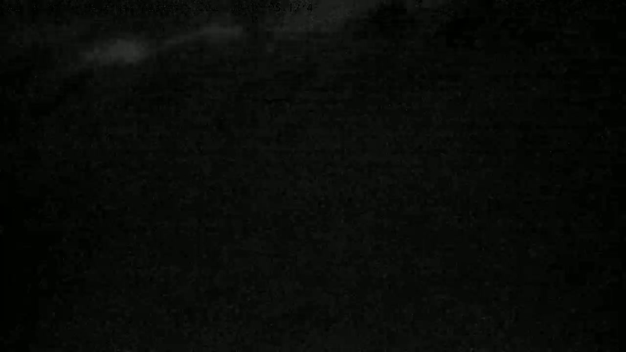 A mostly dark image shows a hazy, light gray area at the top, suggesting nighttime or low-light conditions with some cloud cover.
