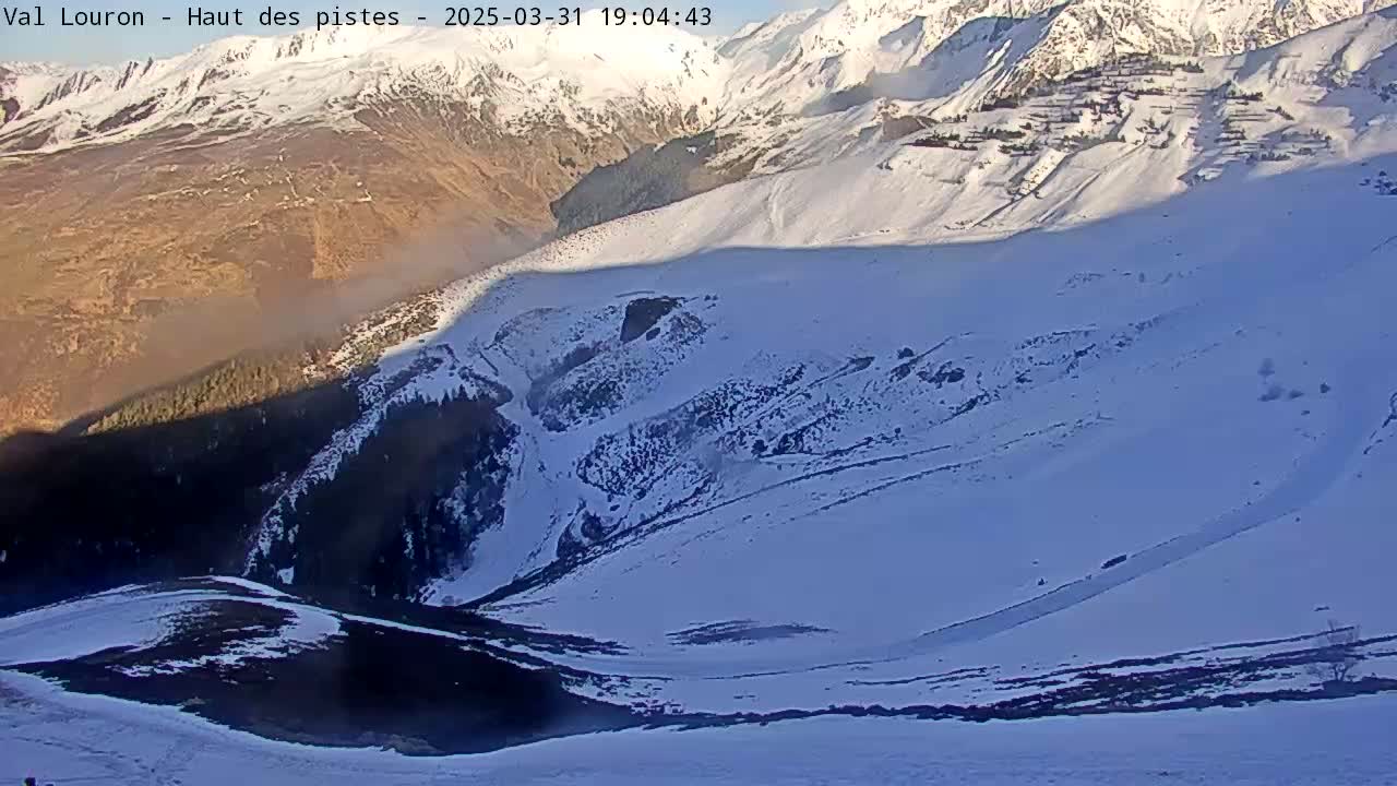 A snow-covered mountain valley is visible, with a shadowed lower portion and a mostly sunny upper portion.