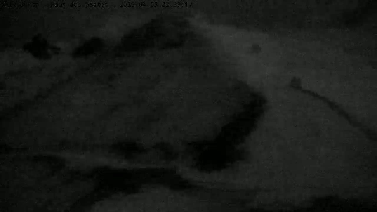 A dark, blurry nighttime image shows indistinct shapes that could possibly be terrain features under a cloudy sky.