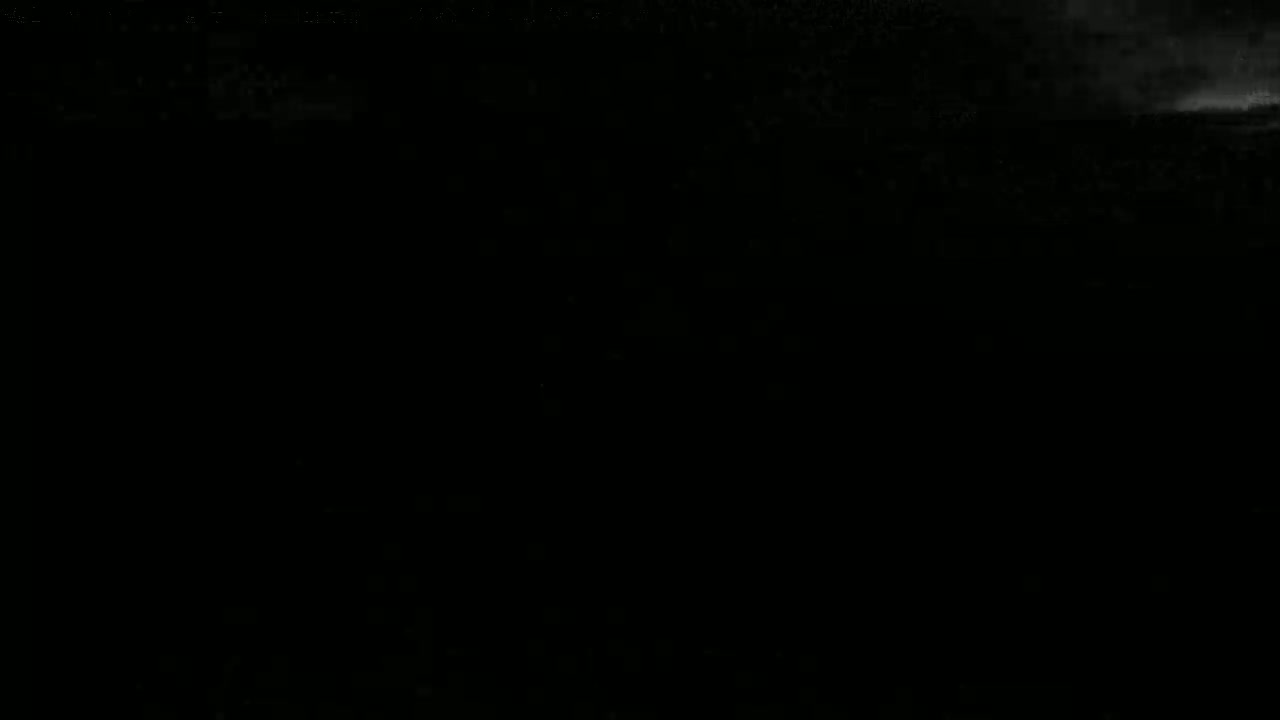 The image shows a mostly dark scene with a faint, bright area at the top, suggesting a nighttime or very low-light outdoor setting with possibly cloudy conditions.