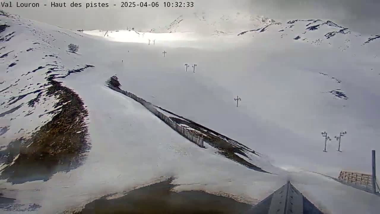 A snow-covered mountain slope with several ski lifts visible under overcast skies.