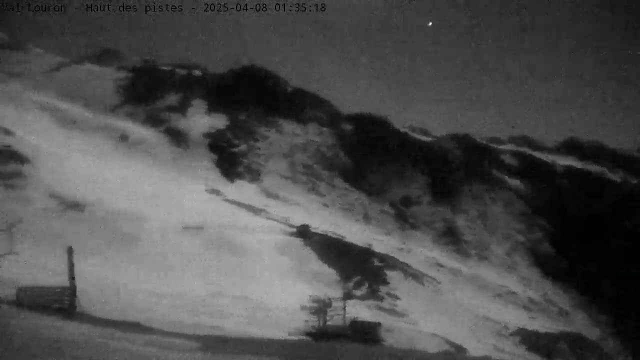 A nighttime, snow-covered hillside is partially obscured by a snow avalanche under a dark sky.