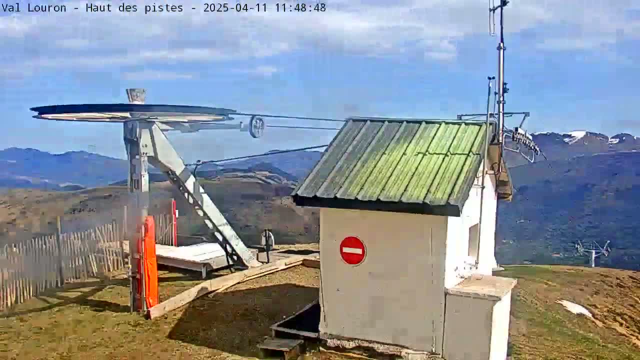 A ski lift terminal building with a mostly clear blue sky and distant mountains in the background.