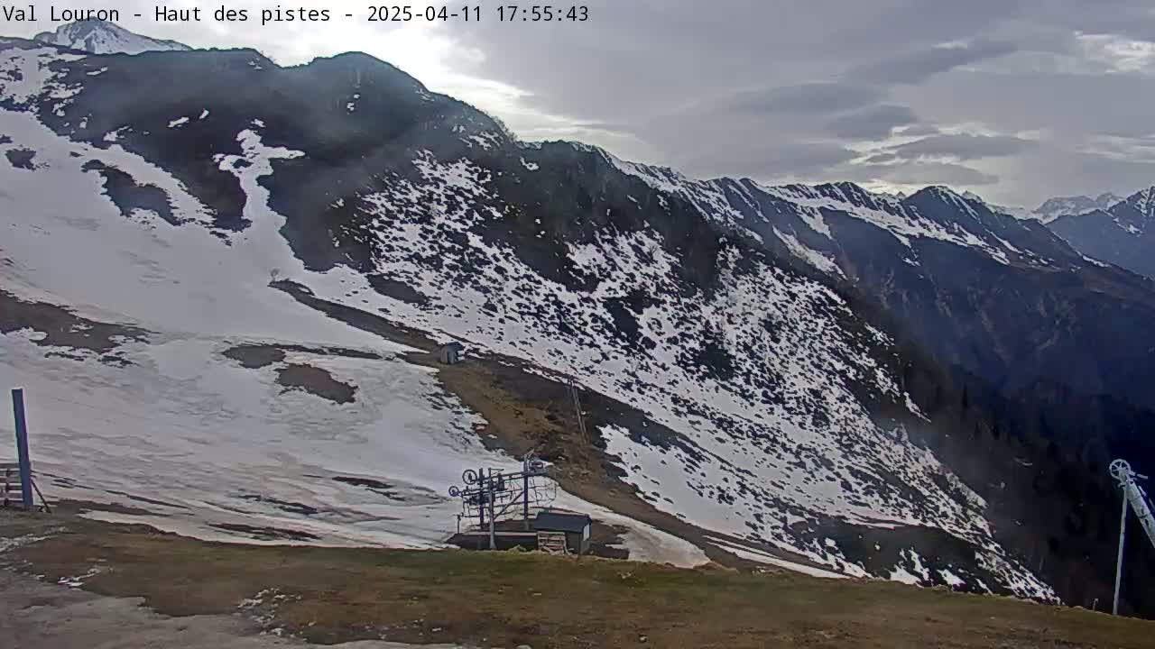 A snow-covered mountain slope with a ski lift and overcast skies.