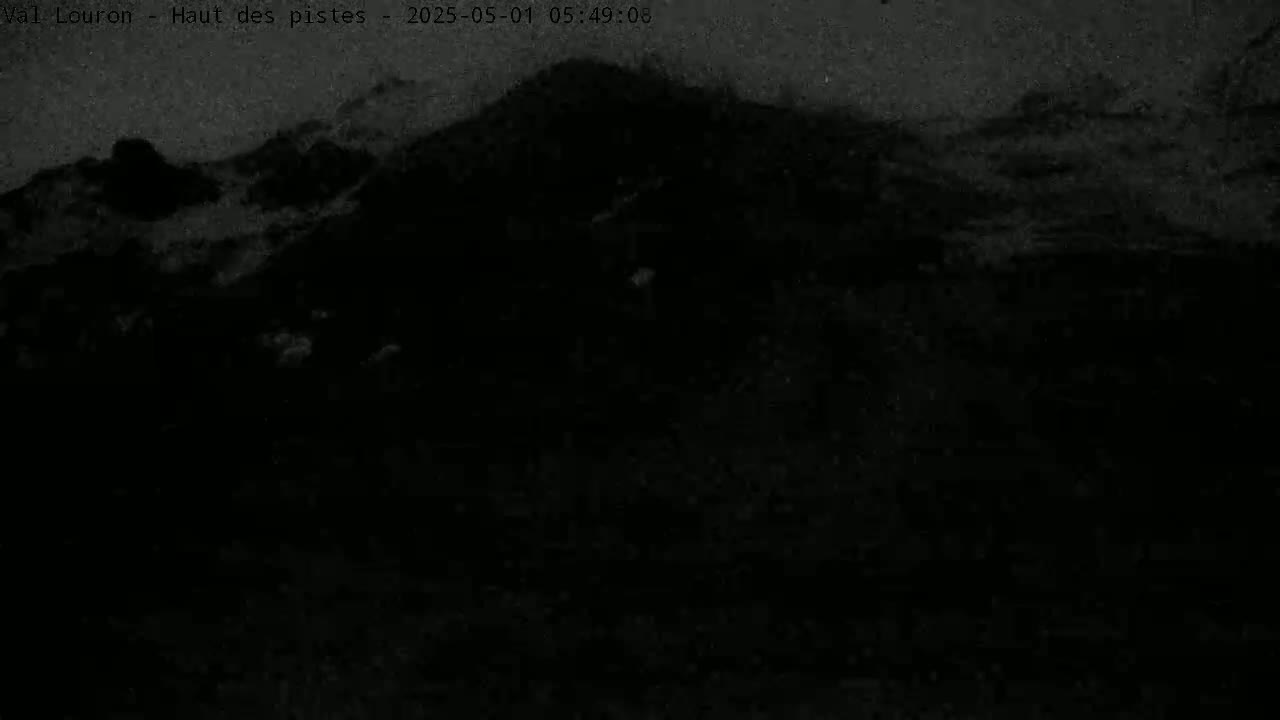 A dark, nighttime view of a snow-covered mountain landscape.