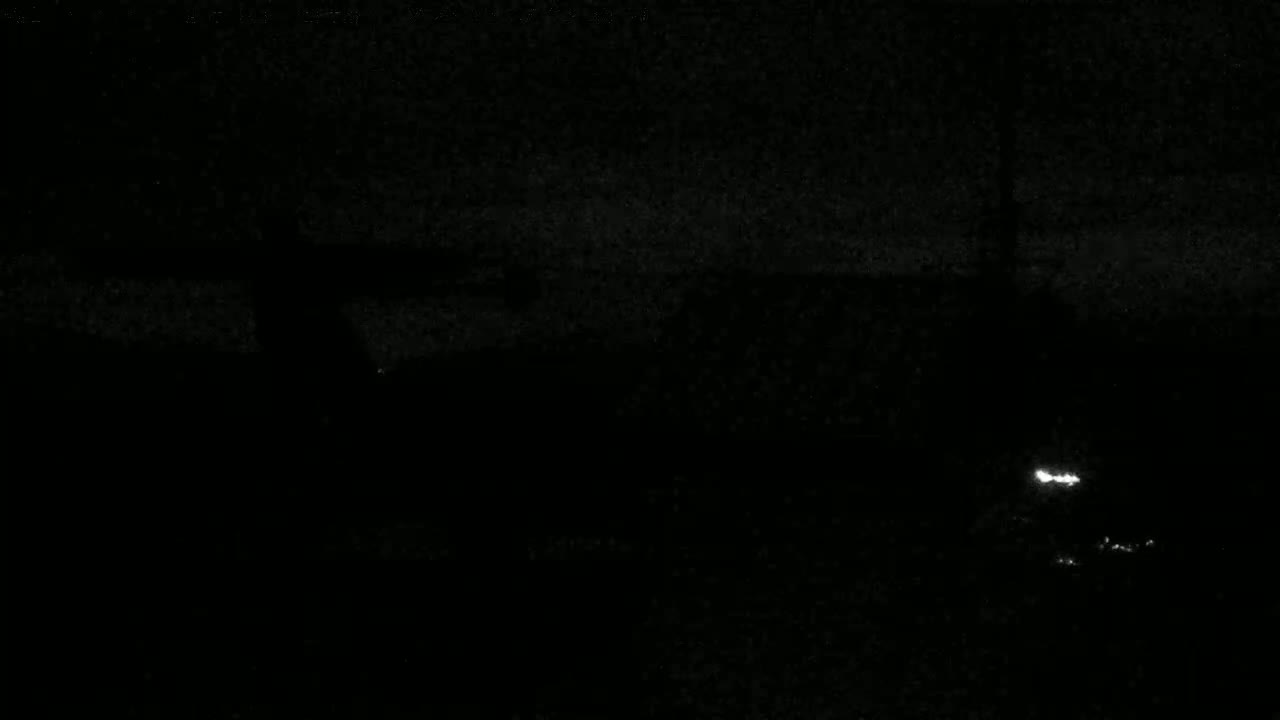 A dark, nighttime scene shows a few faint lights in the distance.