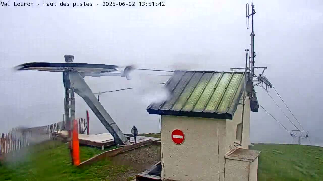 A ski lift mechanism is shown in foggy conditions, alongside a small building with a no entry sign.