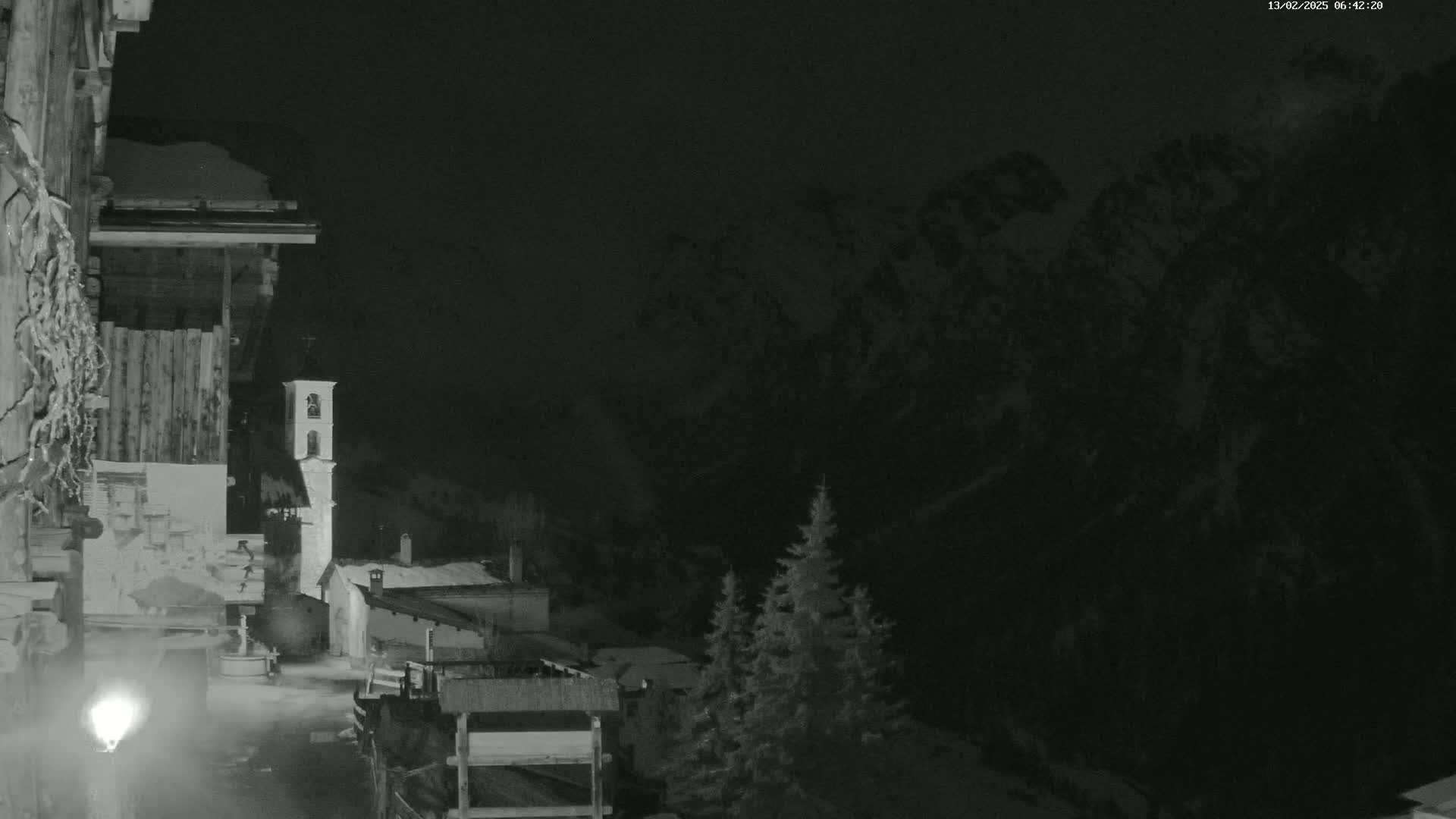 A nighttime, snow-covered village nestled in a valley, overlooked by dark mountains.