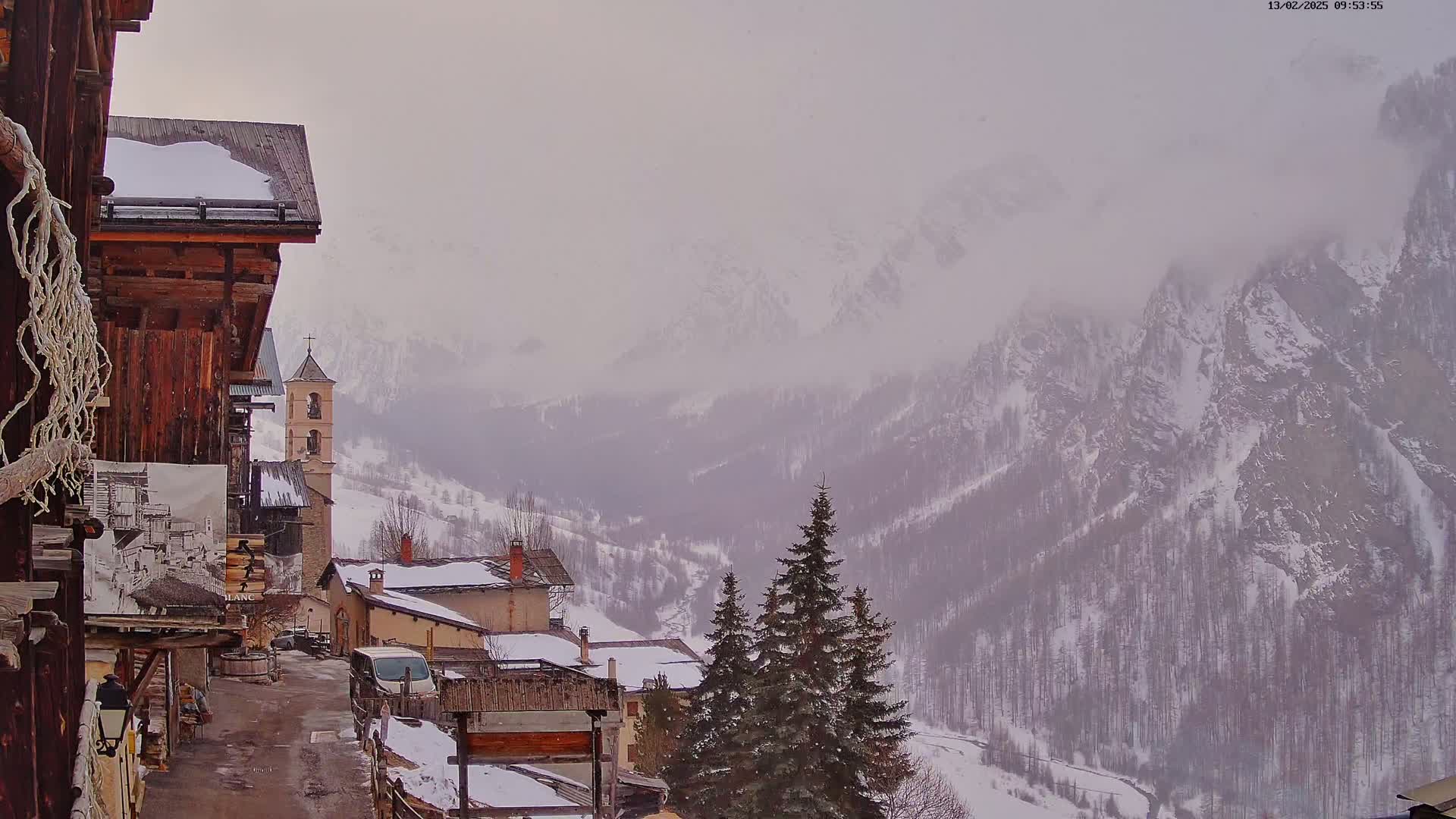 A snow-covered village nestled in a valley between misty, snow-capped mountains.