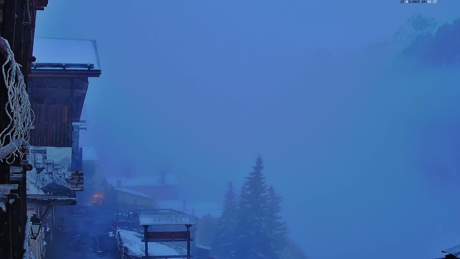 A snow-dusted village is shrouded in thick blue fog.