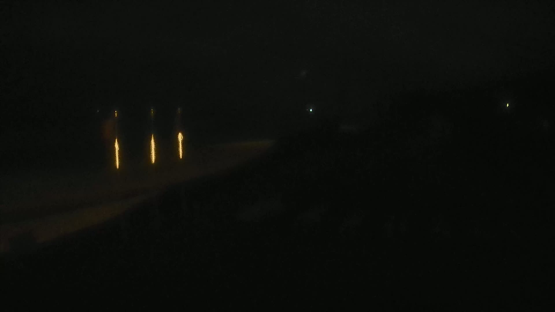 Several vertical streaks of golden light appear against a dark, nighttime background.