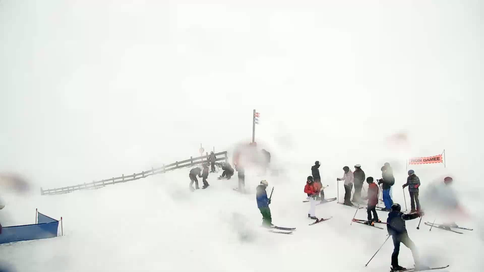 Several skiers and snowboarders are on a snowy slope in a heavy snowstorm.