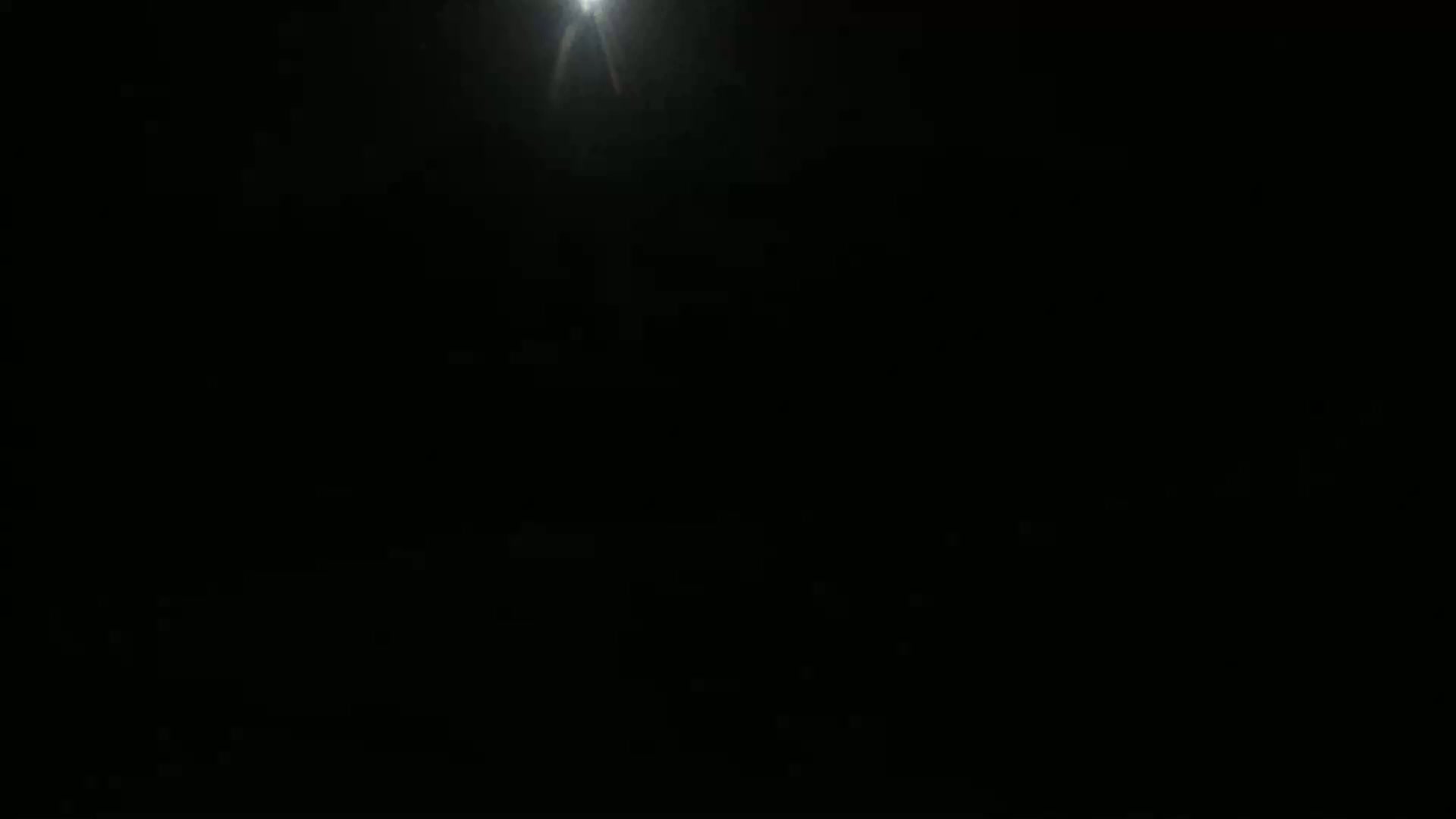 A bright light shines from the top center of a completely dark background.