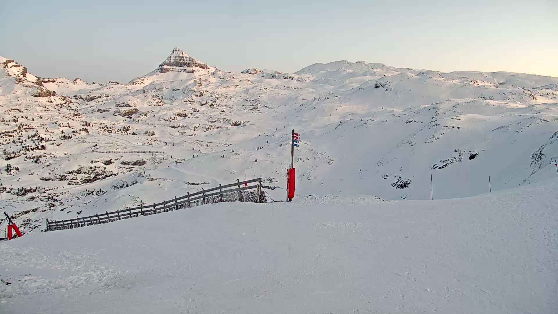 A snow-covered mountain range is viewed from a ski slope on a clear, bright day.