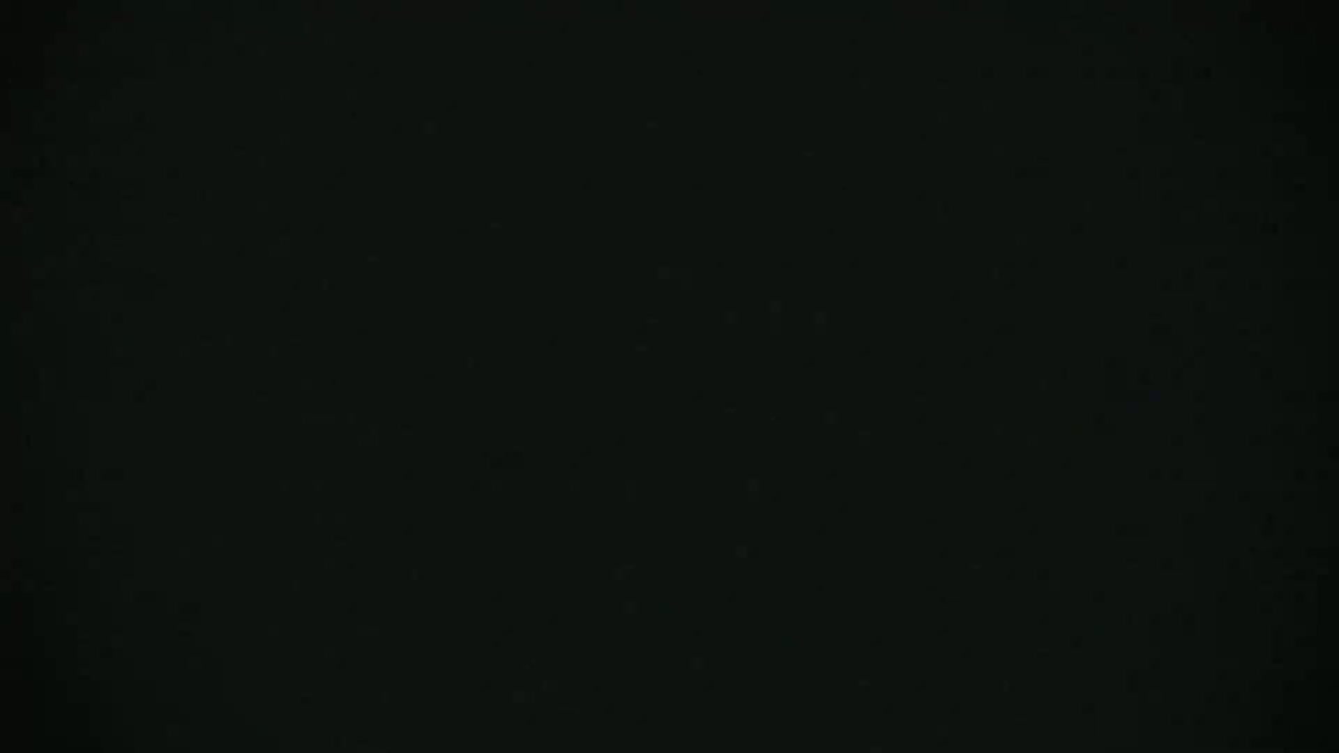 The image shows a completely black screen with a few tiny, scattered specks of lighter color.