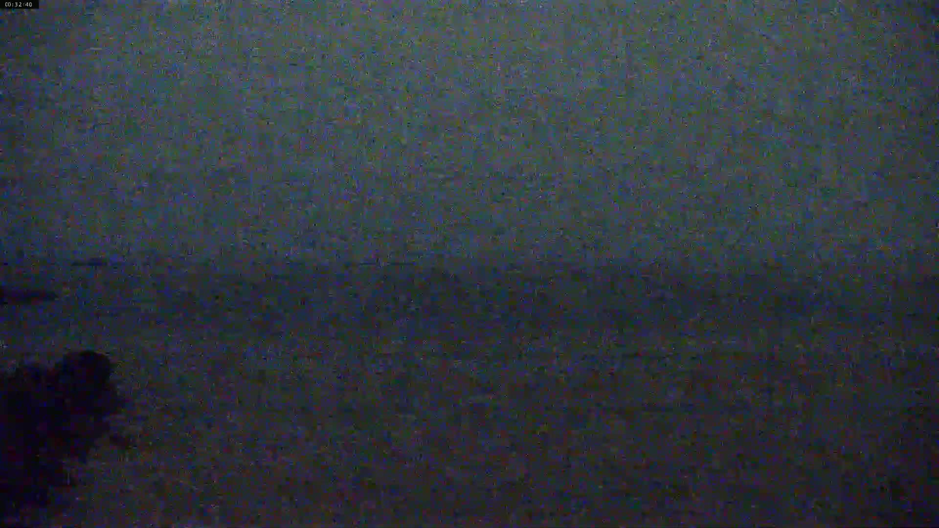 A low-light, dark image shows a body of water under a dark, possibly nighttime sky.