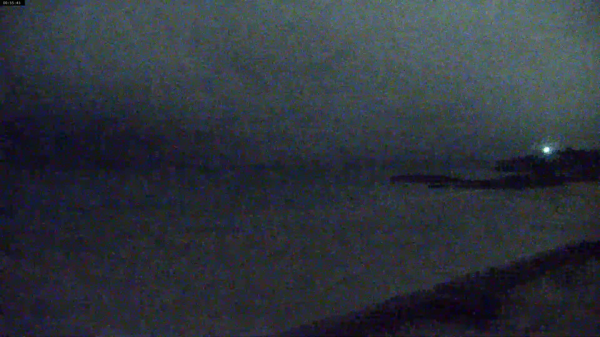 A dark, nighttime view of a body of water under a hazy sky.