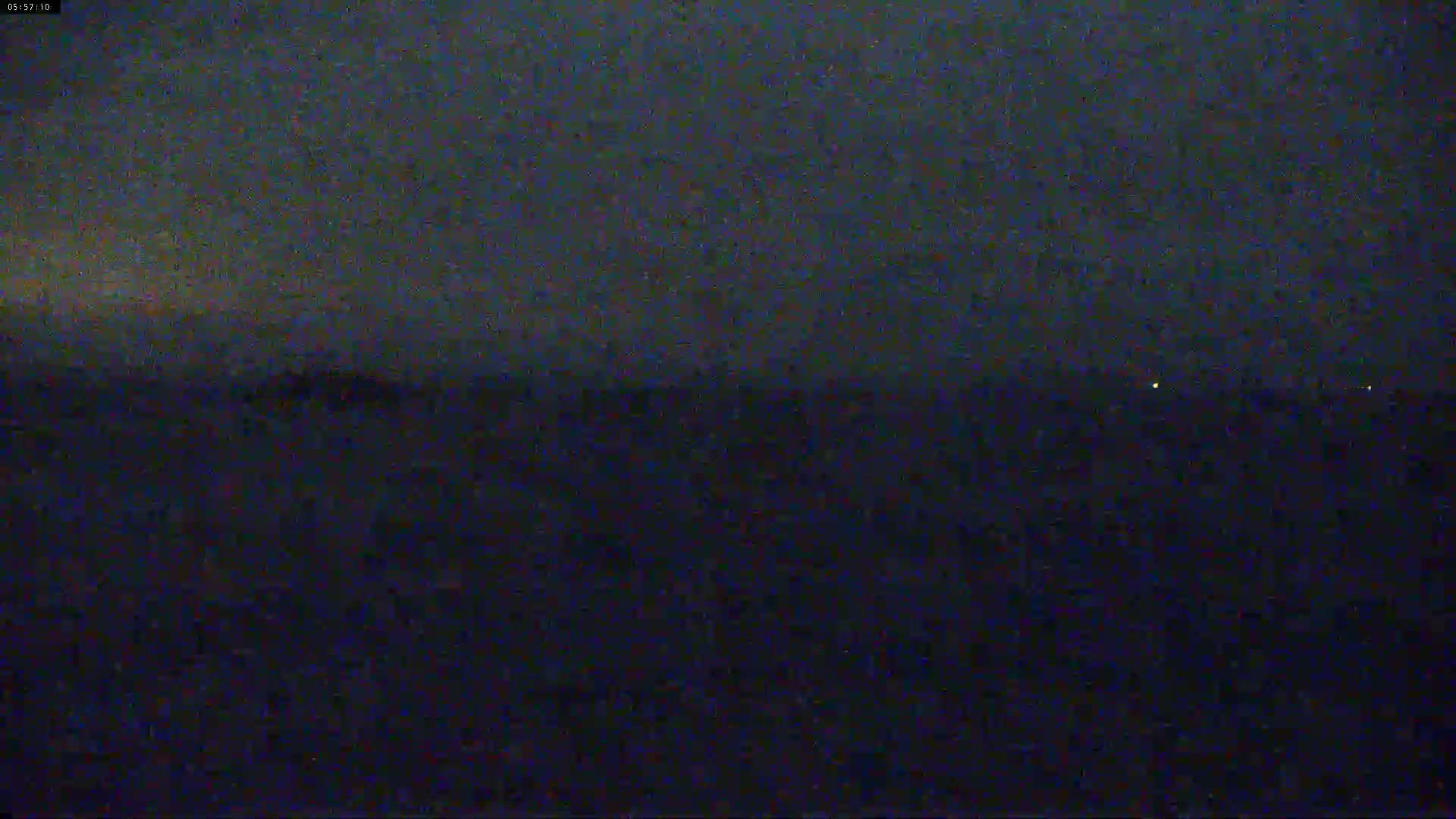 A dark, nighttime landscape is visible under a mostly cloudy sky.