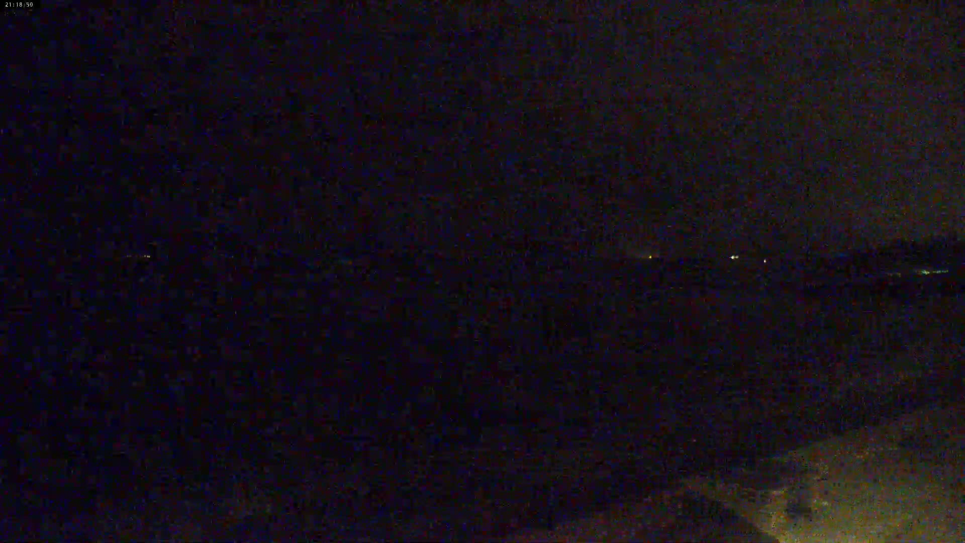 A dark, nighttime scene shows a distant horizon with a few faint lights.