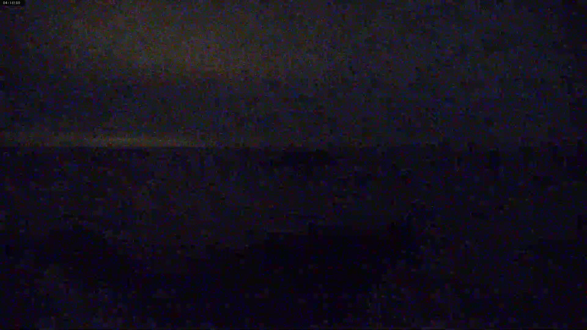 A dark, nighttime outdoor scene shows a mostly-clear sky over a dark body of water.