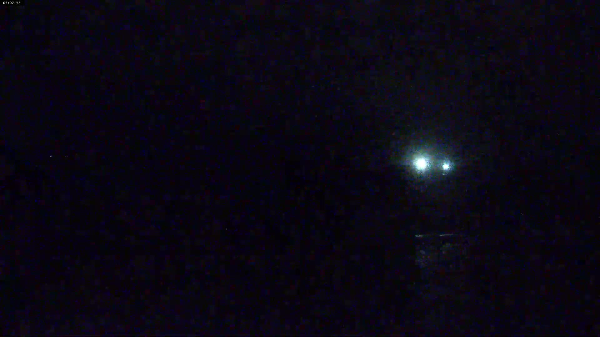 At night, two bright lights are visible in the distance, possibly from vehicles or lights on the ground.