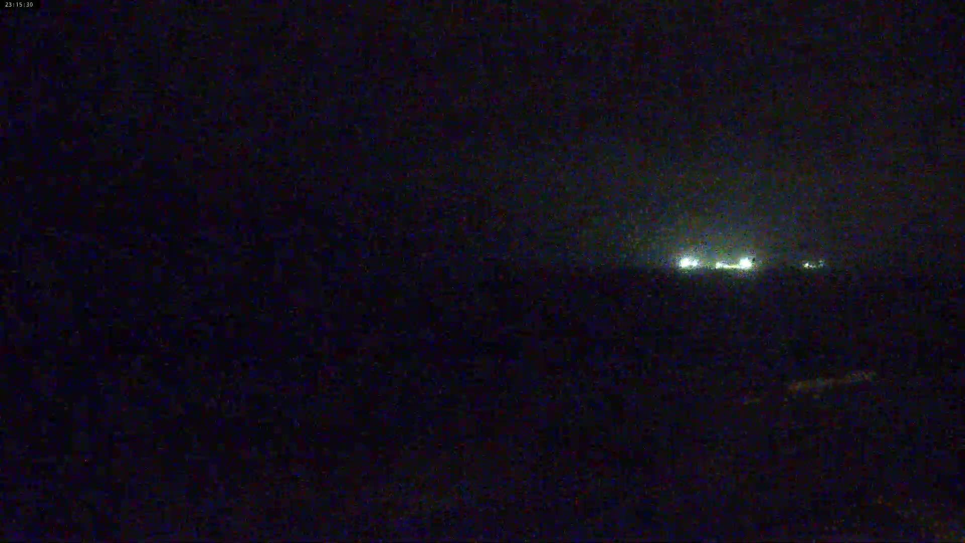 A nighttime, dark view shows a distant line of faint lights in the dark.