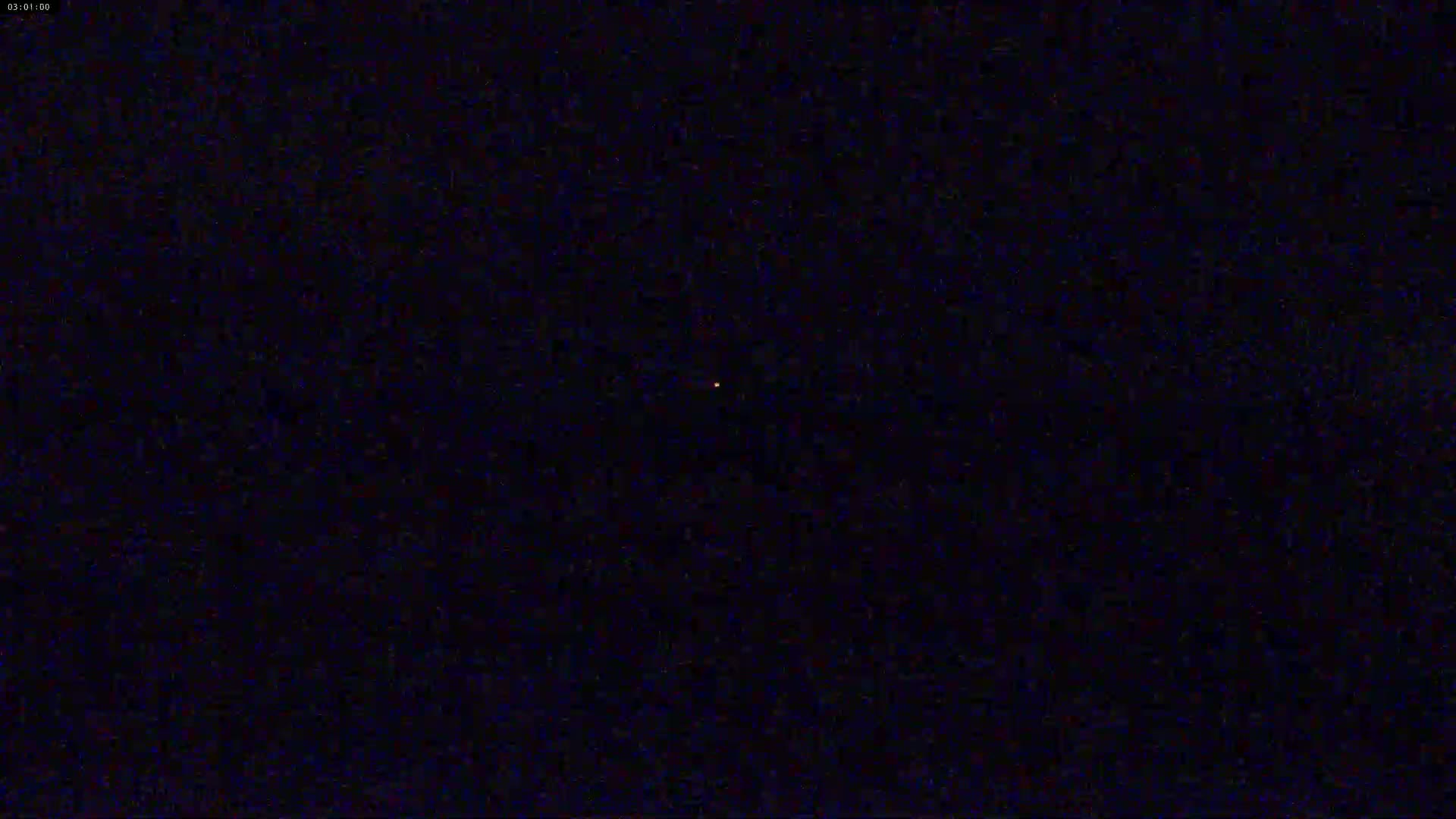A single, small, orange light is visible in the center of a dark, nighttime sky.
