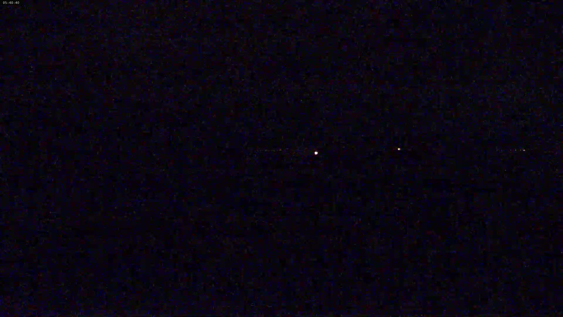 A nighttime image shows three faint lights in a dark sky.