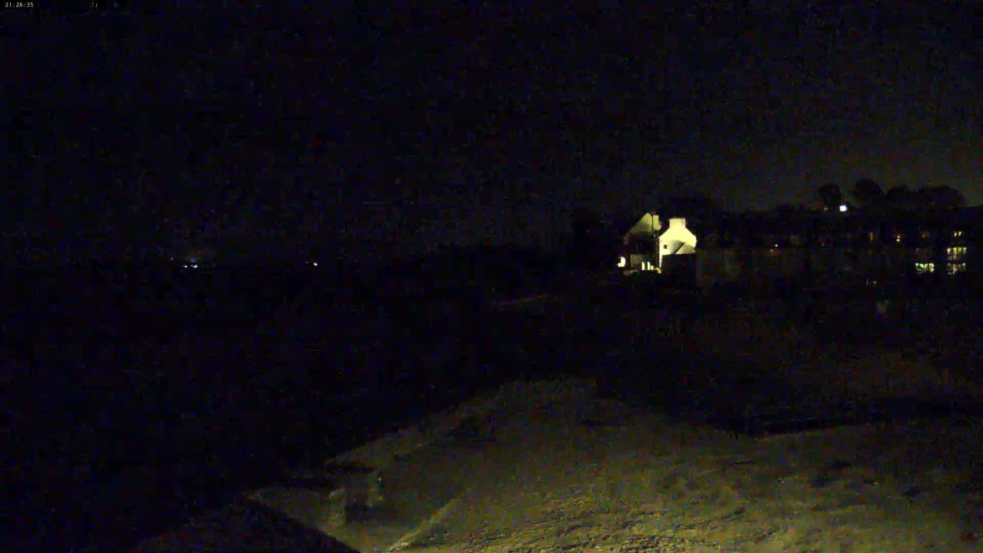 A nighttime view shows dimly lit houses and a dark, possibly snowy, foreground under a clear sky.