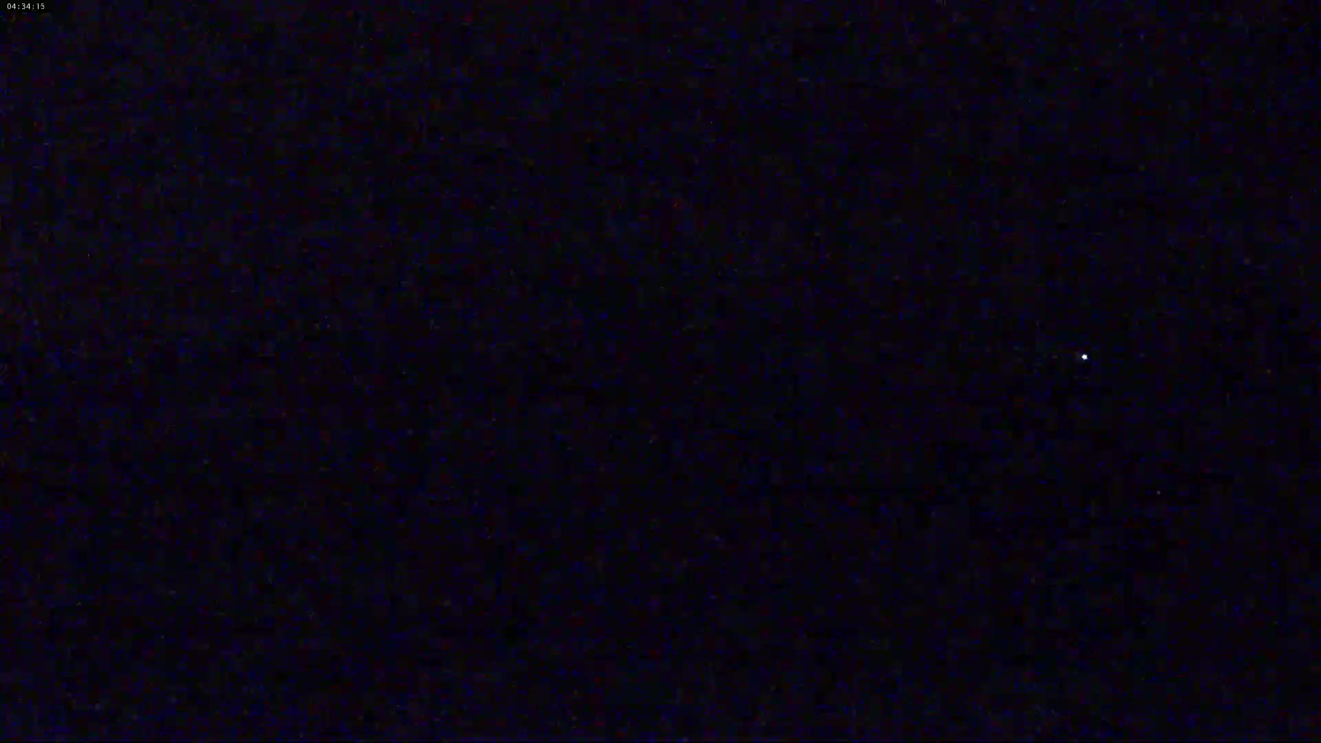 A single, small, bright light is visible in a dark, nighttime sky.