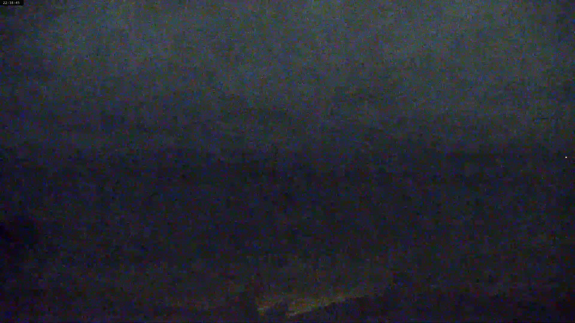 A dark, blurry nighttime image shows a mostly indistinct landscape under an overcast sky.