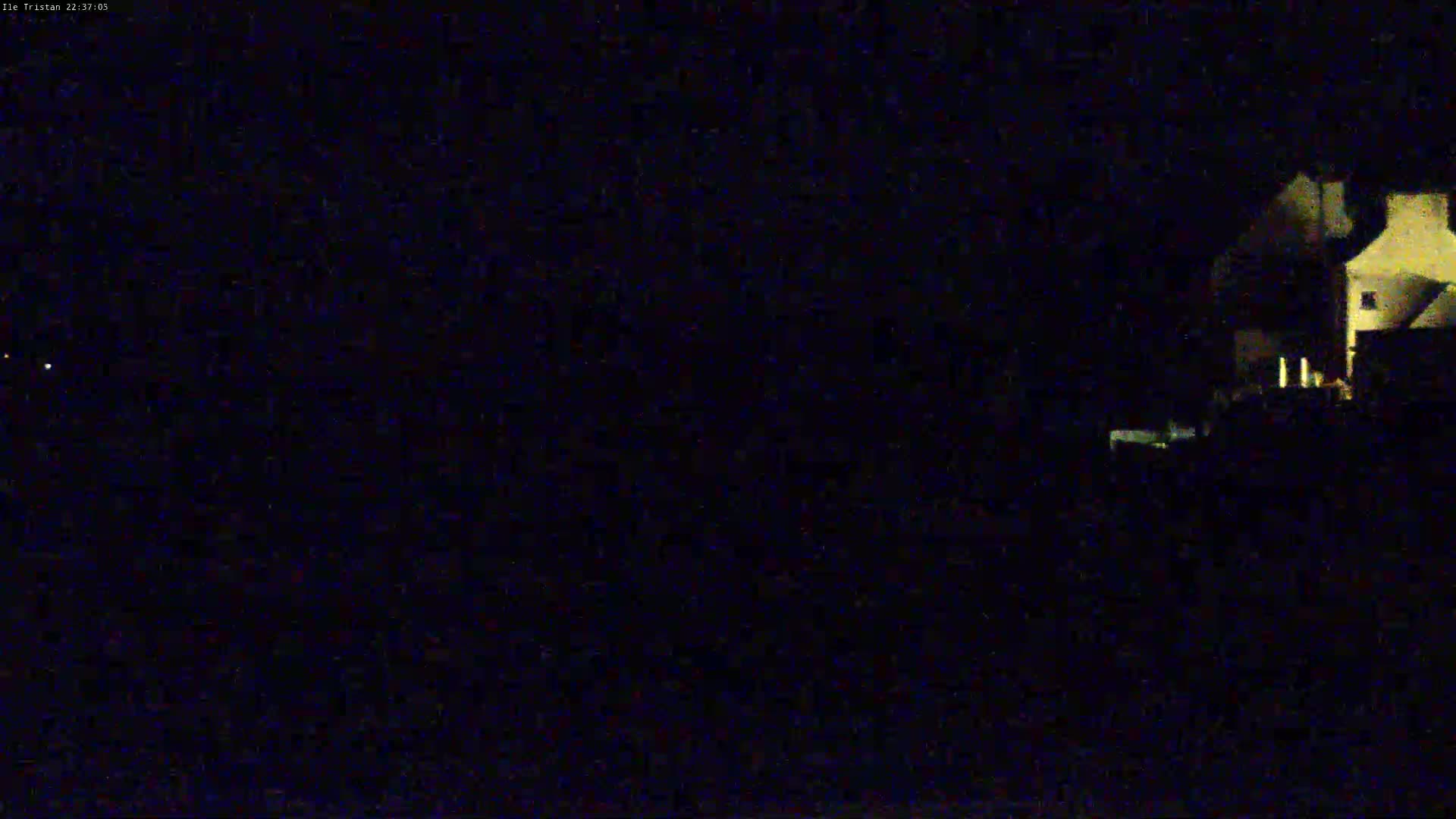 A dimly lit house is visible at night under a dark sky.