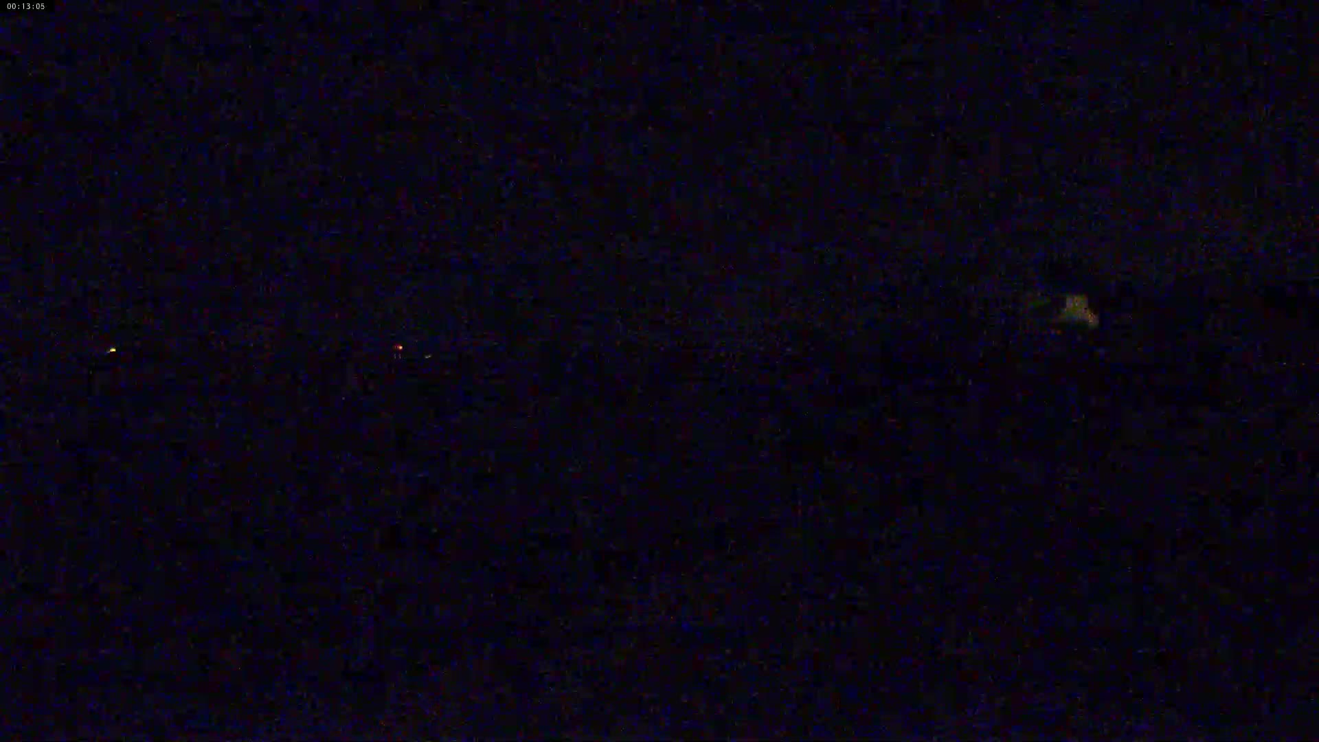 A dark, nighttime scene shows a few faint lights in the distance.