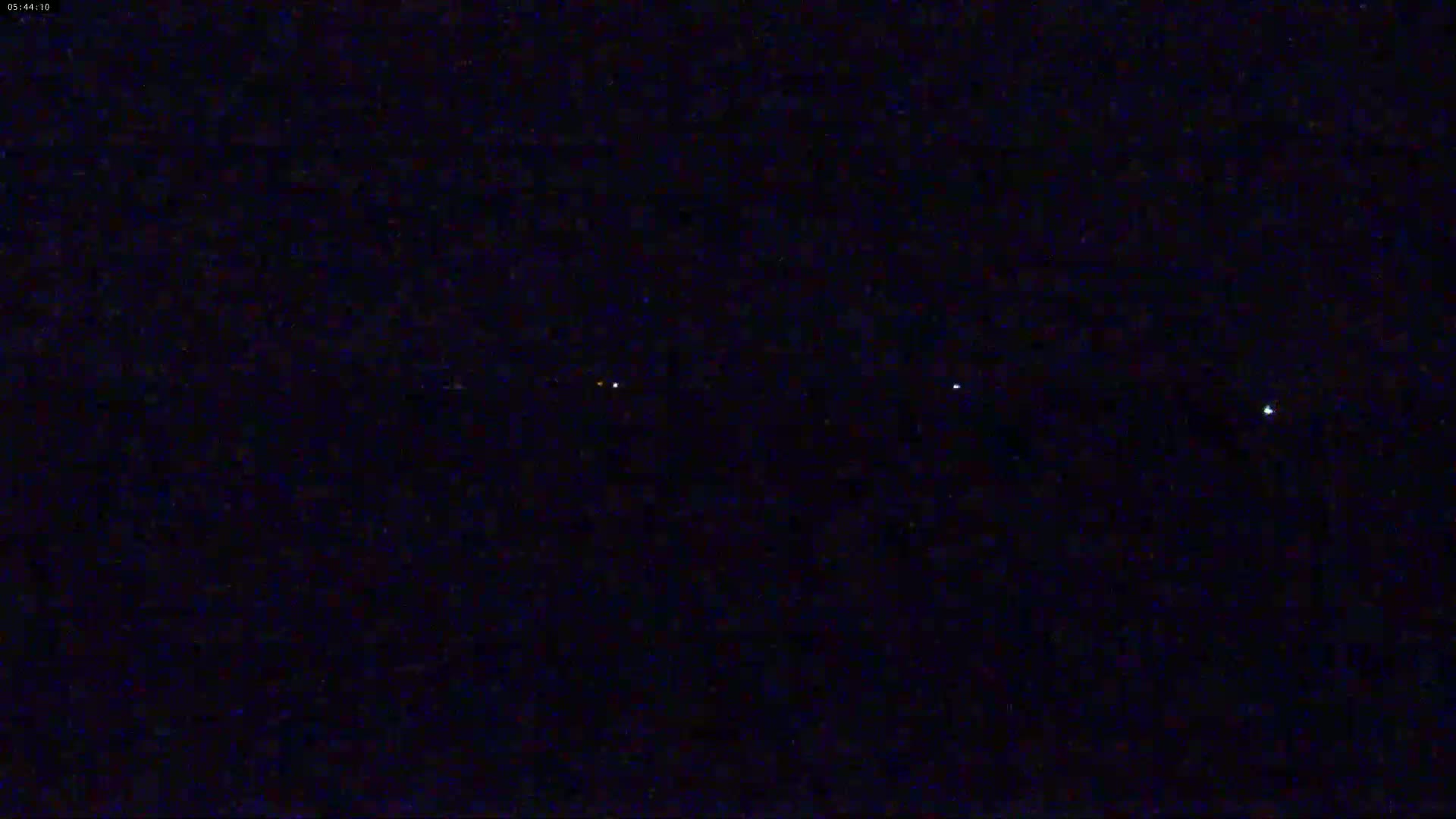 A nighttime scene shows a few small, distant lights in the dark.
